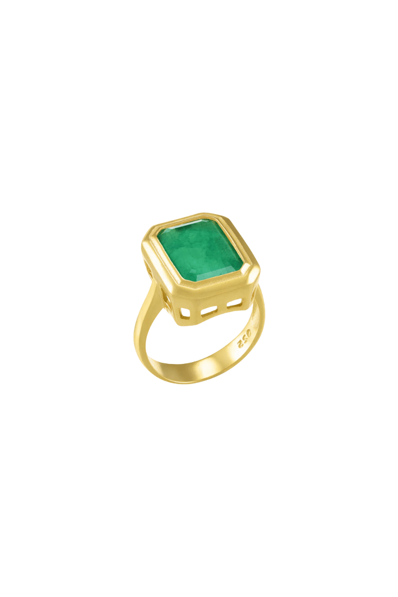 A gold ring featuring a large, emerald-cut green gemstone in a bezel setting, shown on a plain white background.