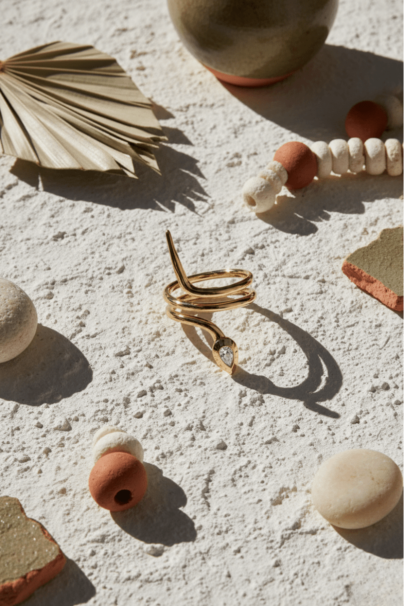 Gold spiral necklace on a textured surface with decorative elements